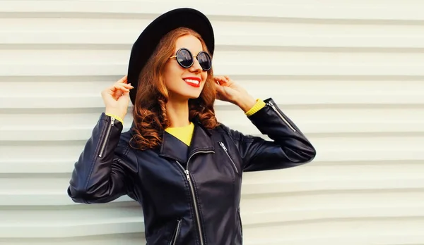 Portrait of stylish young woman model posing wearing black rock style jacket on white background