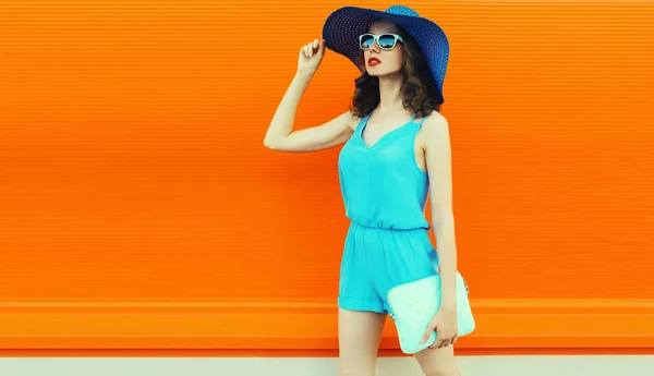 漂亮的年轻女模特穿着夏草帽 蓝色的衣服在城市街道上的橙色背景 — 图库照片