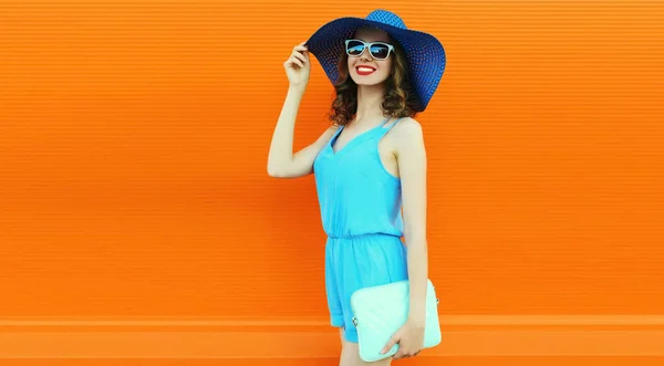 美丽笑容可亲的年轻女模特的画像 戴着夏草帽 蓝色的裙装笼罩着橙色背景 空白的广告版面 — 图库照片