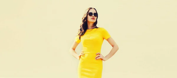 美しいブルネットの若い女性の肖像 都市の通りの背景に黄色のドレスを着て — ストック写真