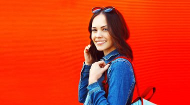 Kırmızı arka planda telefonla konuşan mutlu, gülümseyen genç bir kadının portresi.