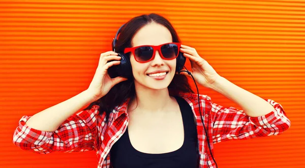 多彩的背景下 用耳机听音乐的快乐微笑的年轻女子的画像 — 图库照片