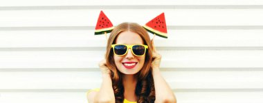 Beyaz arka planda dondurma şeklinde karpuz dilimiyle gülümseyen mutlu genç bir kadının yaz portresi.