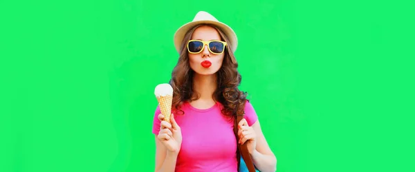 幸せな若いです女性吹いて彼女の唇とともにアイスクリーム身に着けている夏のわら帽子上の緑の背景 — ストック写真