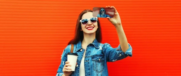 笑容满面的年轻女子用红底背包智能手机自拍的画像 — 图库照片