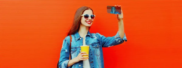 幸せな笑顔の若い女性の肖像写真でスマートフォンで撮影バックパックで赤の背景 ストック画像
