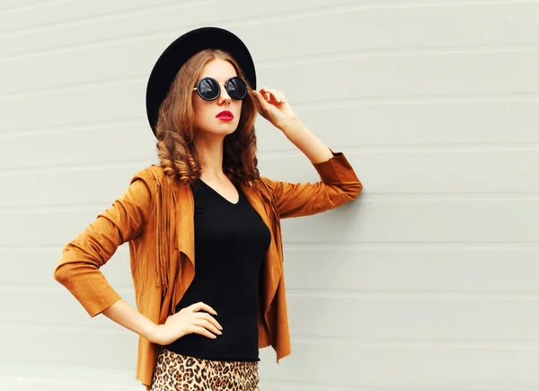 黒丸帽子を身に着けている美しいスタイリッシュな若い女性の肖像画 グレーの背景に茶色のジャケット — ストック写真