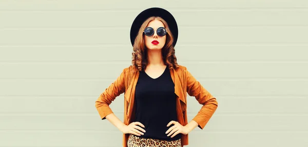 黒丸帽子を身に着けている美しいスタイリッシュな若い女性の肖像画 グレーの背景に茶色のジャケット — ストック写真