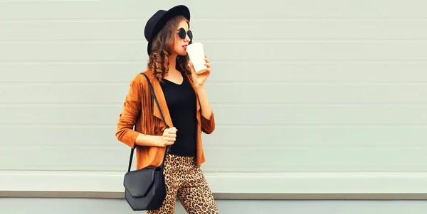 黒丸帽子 茶色のジャケットとグレーの背景にハンドバッグを身に着けている美しいスタイリッシュな女性モデル — ストック写真