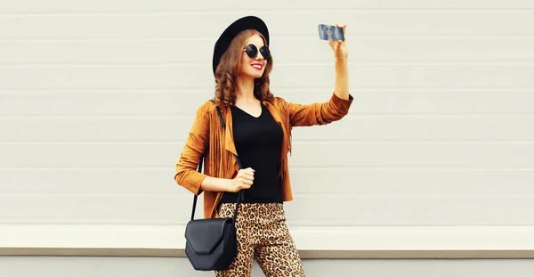 スタイリッシュで幸せな笑顔の若い女性の肖像写真付きスマートフォンによってグレーの背景 ストックフォト