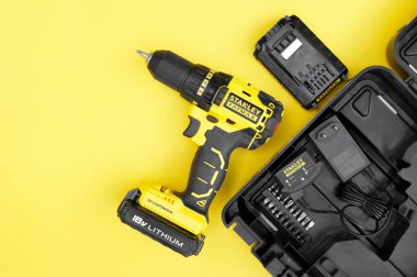 Sarı arka planda sarı-siyah tornavida, vidalar, birkaç parça..