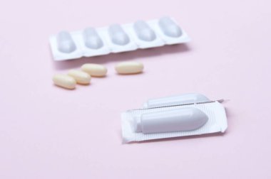 Kadın sağlığı için fitil şeklinde jinekolojik ilaçlar, pembe arka planda kapsüller. Vulvovaginal enfeksiyon tedavisi.