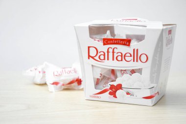 KHARKIV, UKRAINE - 23 Ekim 2021: Raffaello tatlılar açık ahşap bir masa ve beyaz zemin üzerinde. Raffaello, İtalyan imalatçı Ferrero 'nun 1990 yılında pazara getirdiği küresel bir hindistan cevizi badem şekerlemesi.