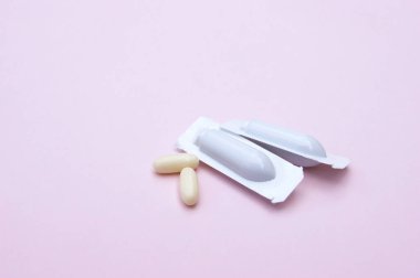 Gynecological medicines for women's health in form of suppository, capsules on pink background. Vulvovaginal infections treatment. clipart