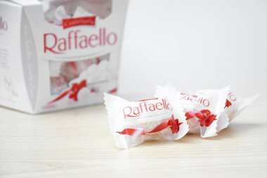 KHARKIV, UKRAINE - 23 Ekim 2021: Raffaello tatlılar açık ahşap bir masa ve beyaz zemin üzerinde. Raffaello, İtalyan imalatçı Ferrero 'nun 1990 yılında pazara getirdiği küresel bir hindistan cevizi badem şekerlemesi.