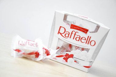 KHARKIV, UKRAINE - 23 Ekim 2021: Raffaello tatlılar açık ahşap bir masa ve beyaz zemin üzerinde. Raffaello, İtalyan imalatçı Ferrero 'nun 1990 yılında pazara getirdiği küresel bir hindistan cevizi badem şekerlemesi.