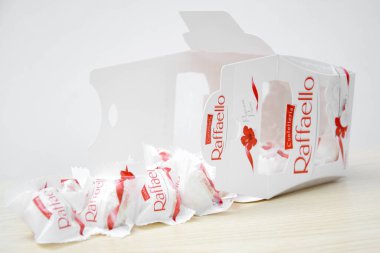 KHARKIV, UKRAINE - 23 Ekim 2021: Raffaello tatlılar açık ahşap bir masa ve beyaz zemin üzerinde. Raffaello, İtalyan imalatçı Ferrero 'nun 1990 yılında pazara getirdiği küresel bir hindistan cevizi badem şekerlemesi.