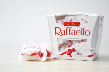 KHARKIV, UKRAINE - 23 Ekim 2021: Raffaello tatlılar açık ahşap bir masa ve beyaz zemin üzerinde. Raffaello küresel bir Hindistan cevizli badem şekerlemesidir..