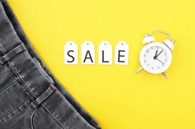 Düz yatış, siyah kot, beyaz etiketler ve sarı arka planda indirim. Alışveriş ve indirim konsepti. Kara Cuma.