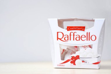 KHARKIV, UKRAINE - 23 Ekim 2021: Raffaello tatlılar açık ahşap bir masa ve beyaz zemin üzerinde. Raffaello küresel bir Hindistan cevizli badem şekerlemesidir..