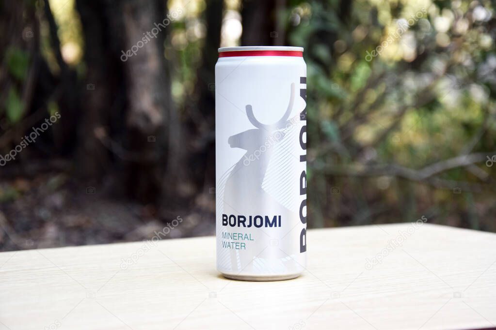 KHARKIV, UKRAINE - OCTOBER 23, 2021: Can of Georgian mineral water BORJOMI in the open air. Borjomi is the most popular mineral water manufactured in a South Central Georgia Resort.