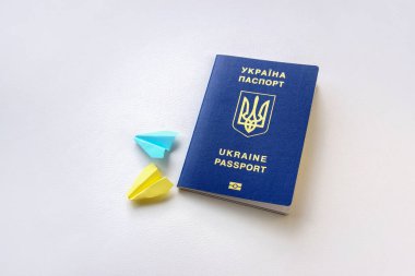 Yeni Ukrayna biyometrik pasaportu ve beyaz arka planda sarı mavi kağıt uçaklar. Seyahat kavramı