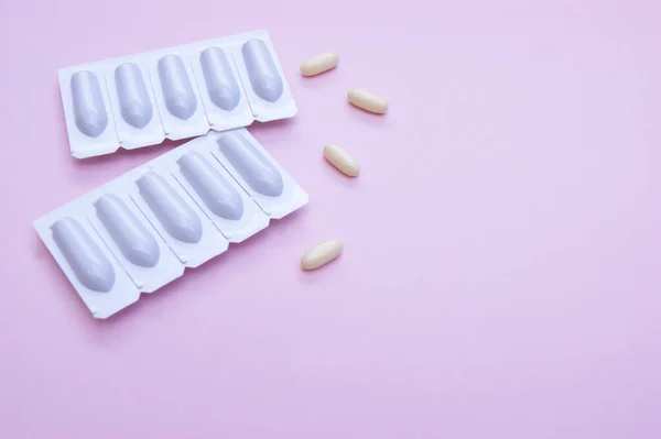 Gynecological medicines for women's health in form of suppository, capsules on pink background. Vulvovaginal infections treatment. Top view.