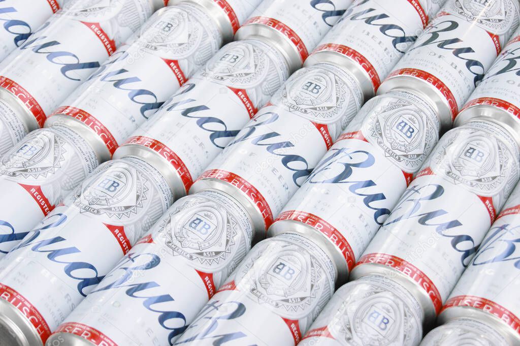 KHARKIV, UKRAINE - AUGUST 1, 2021: Many Cans of Budweiser Lager Alcohol Beer lies on grey background. Budweiser is Brand from Anheuser-Busch Inbev most popular in America