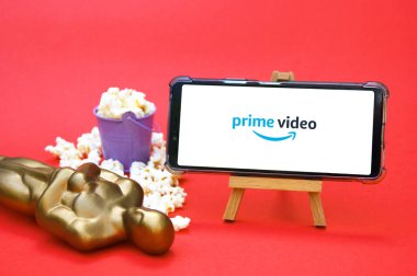KHARKIV, UKRAINE - 1 Haziran 2020: Prime video stüdyo logosuna sahip akıllı telefon, Oscar figürü ve patlamış mısır. Film endüstrisi kavramı.
