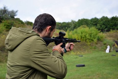 KHARKIV, UKRAINE - 4 Eylül 2021: Genç bir adam AR 15 tüfeğiyle çatışma eğitimi aldı. Ateşli silahlar. Atış galerisi.