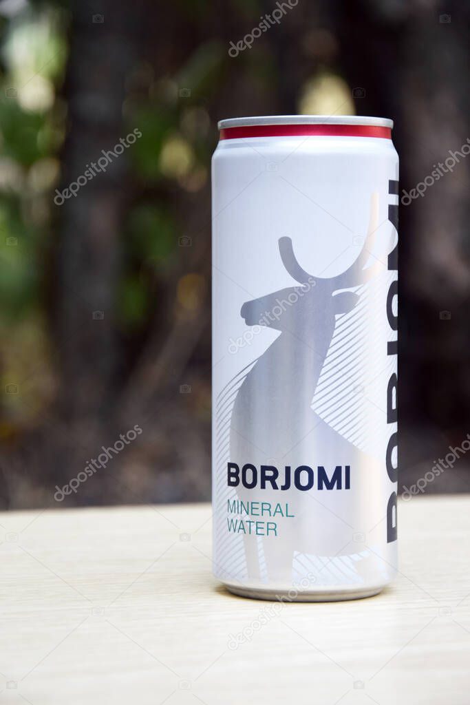 KHARKIV, UKRAINE - OCTOBER 23, 2021: Can of Georgian mineral water BORJOMI in the open air. Borjomi is the most popular mineral water manufactured in a South Central Georgia Resort.