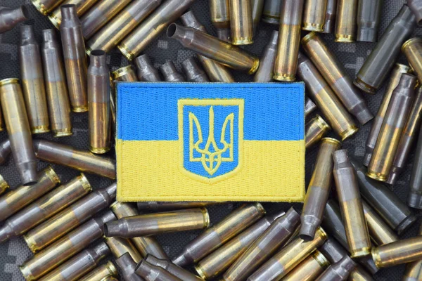 シェルに囲まれた軍事カモフラージュの背景に腕のコートを持つウクライナの国旗 ウクライナでの戦争 戦争をやめろ — ストック写真