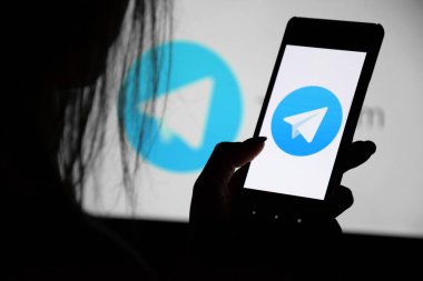 Kharkiv, Ukrayna - 20 Aralık 2021: Monitörün arka planında genç bir kızın elinde bir telgraf ekranı olan bir telefon. Seçici odak.