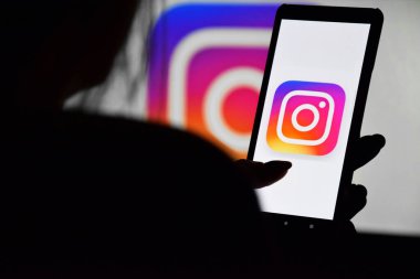 Kharkiv, Ukrayna - 20 Aralık 2021: Instagram ekranlı bir telefon genç bir kızın elinde bir monitörün arka planına karşı. Seçici odak.