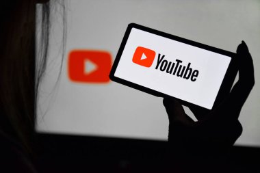 Kharkiv, Ukrayna - 20 Aralık 2021: Bir ekranın arka planında genç bir kızın elinde YouTube ekranı olan bir telefon. Seçici odak.