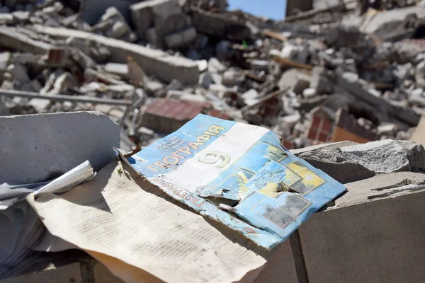 Kharkiv, Ukraine - May 7, 2022: a geography textbook for grade 9 against the backdrop of a bombed-out school in the city of Kharkov. The results of the war. War in Ukraine.