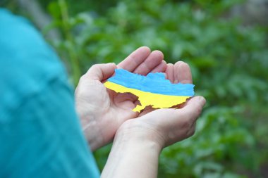 Ukrayna 'nın ulusal bayrağı gibi mavi ve sarıyla süslenmiş bir kadın elinde Ukrayna' nın ana hatlarını tutuyor. Bağımsızlık, bayrak, Anayasa Günü. Ukrayna 'da Savaş.