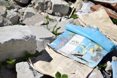 Kharkiv, Ukraine - May 7, 2022: a geography textbook for grade 9 against the backdrop of a bombed-out school in the city of Kharkov. The results of the war. War in Ukraine.