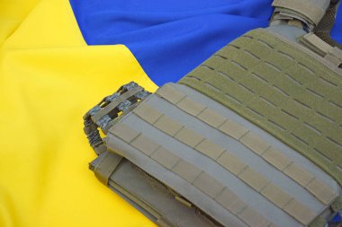 Ukrayna bayrağının arka planında plakası olan taktik ve askeri zırh. Ukrayna 'daki savaşta vücudunu kurşunlardan koruma kavramı.
