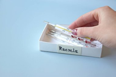 Eski civa termometreleri ve çevresel ve toprak toksik maddelerin mavi arka planda düzgün bir şekilde imha edilmesi. Zararlı ve geri dönüşümlü nesnelerin işlenmesi kavramı.