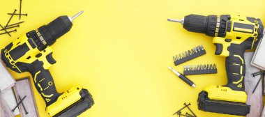 Sarı arka planda sarı-siyah tornavida, vidalar, birkaç parça. Boşluğu kopyala.