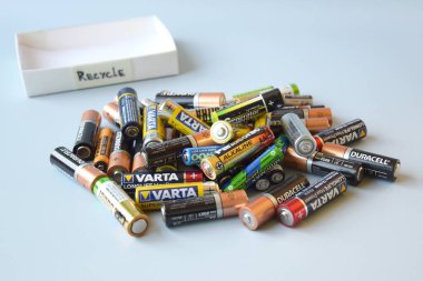 KHARKIV, UKRAINE - 22 Şubat 2022: Kullanılmış AA bataryalar ve çevresel ve toprak zehirli bataryaların mavi arka planda düzgün bir şekilde imha edilmesi. Zararlı ve geri dönüşümlü nesnelerin işlenmesi kavramı.