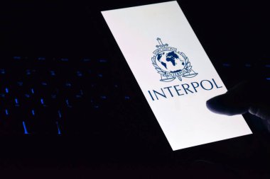 Kharkiv, Ukrayna - 16 Haziran 2022: İnterpol logosu ekranda gösterilen akıllı telefonu tutan kişi. Uluslararası Suç Polis Örgütü veya Interpol.