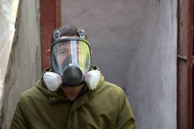 Bomba sığınağında solunum cihazına bağlı genç bir adam. Karanlık fotoğraf. Covid 19 'dan kişisel güvenlik, toksik çalışma, kimyasal silahlar, nükleer tehdit.