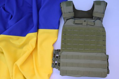 Ukrayna bayrağının arka planında plakası olan taktik ve askeri zırh. Ukrayna 'daki savaşta vücudunu kurşunlardan koruma kavramı.
