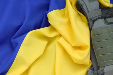 Ukrayna bayrağının arka planında plakası olan taktik ve askeri zırh. Ukrayna 'daki savaşta vücudunu kurşunlardan koruma kavramı.