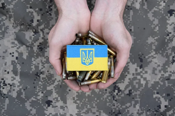 Kirli erkek elleri üzerinde Ukrayna bayrağı olan boş kovanları tutuyor. Ukrayna 'da savaş. Savaşı durdurun..