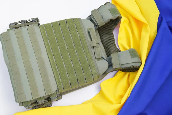 Tactical, military body armor with plates on the background of the flag of Ukraine. The concept of protecting the body from shots in the war in Ukraine.