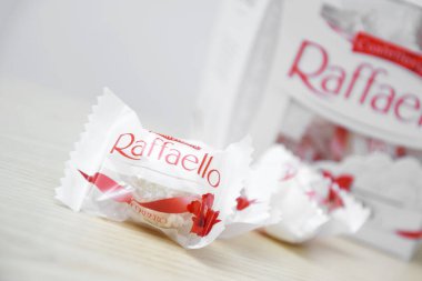 KHARKIV, UKRAINE - 23 Ekim 2021: Raffaello tatlılar açık ahşap bir masa ve beyaz zemin üzerinde. Raffaello küresel bir Hindistan cevizli badem şekerlemesidir..