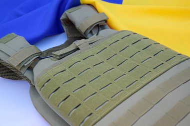 Ukrayna bayrağının arka planında plakası olan taktik ve askeri zırh. Ukrayna 'daki savaşta vücudunu kurşunlardan koruma kavramı.
